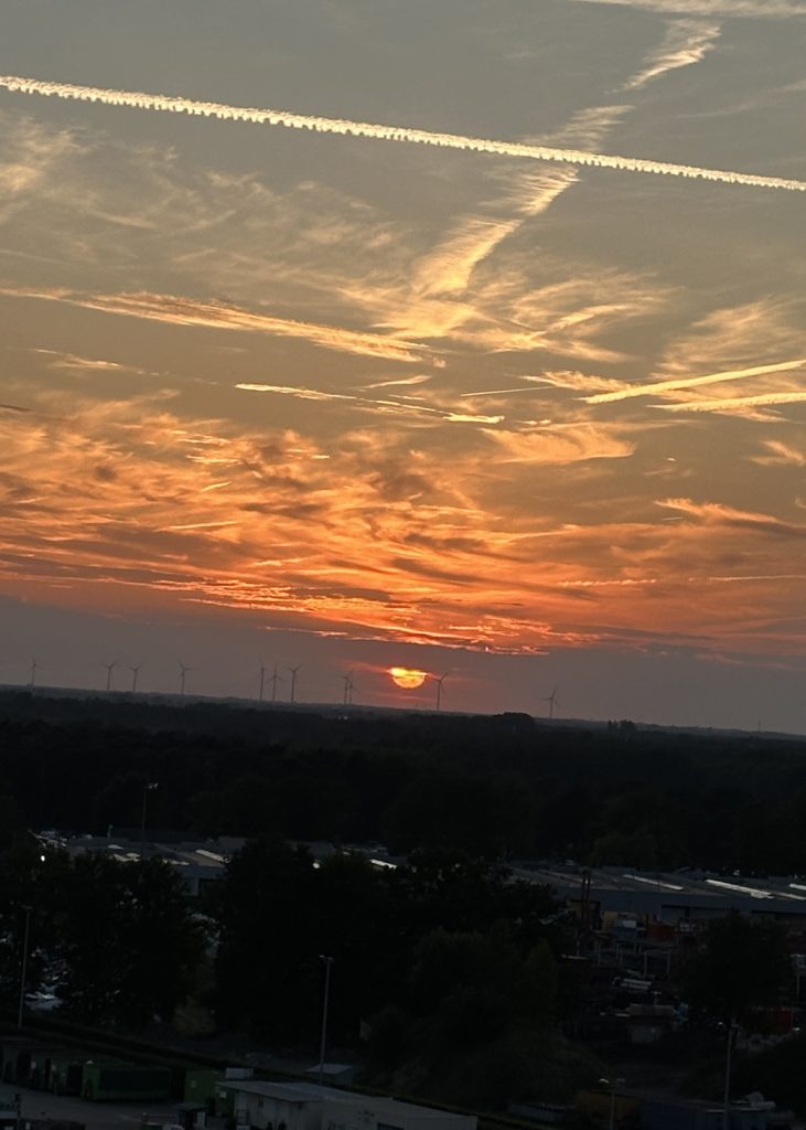 The image shows a sunset, the sun is low on the horizon, casting warm hues—orange, and yellow across the sky