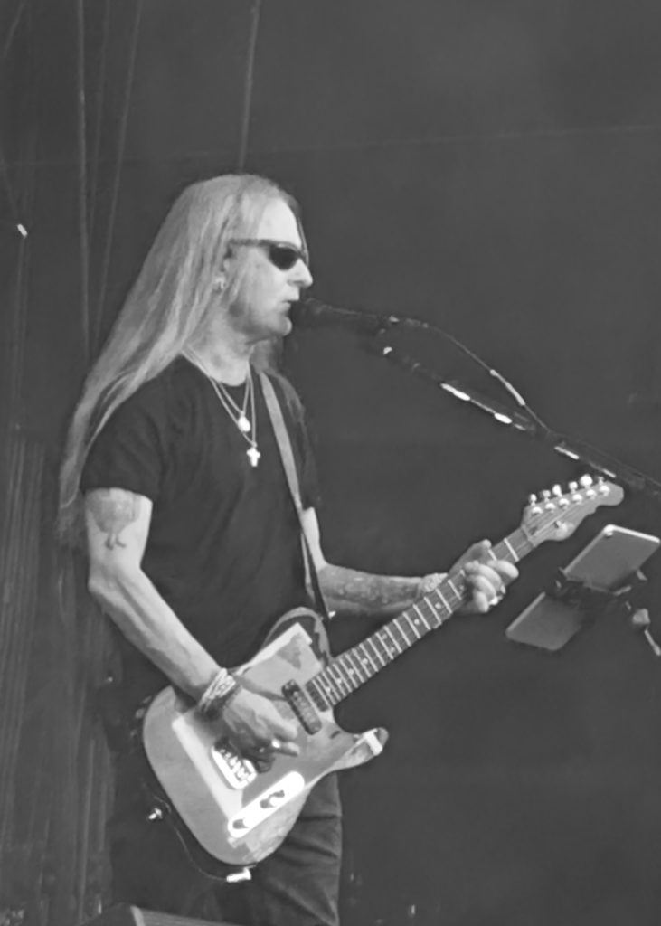 The image shows Jery Cantrell on stage during a live performance. He sings and plays the guitar